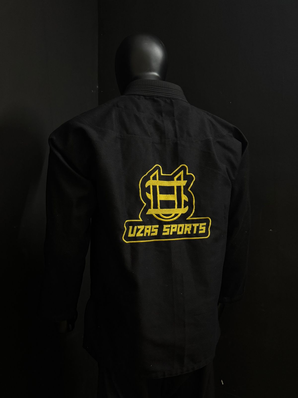 Black martial arts jacket with a large gold embroidered back logo