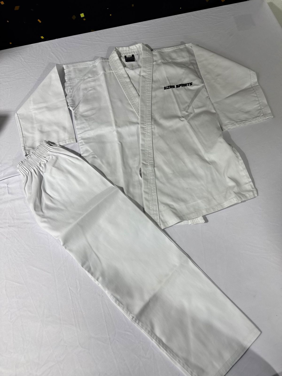 White karate uniform jacket and pants laid flat