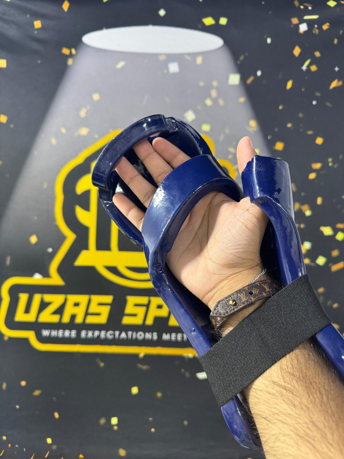 Blue taekwondo hand guard in front of the UZAS Sports backdrop