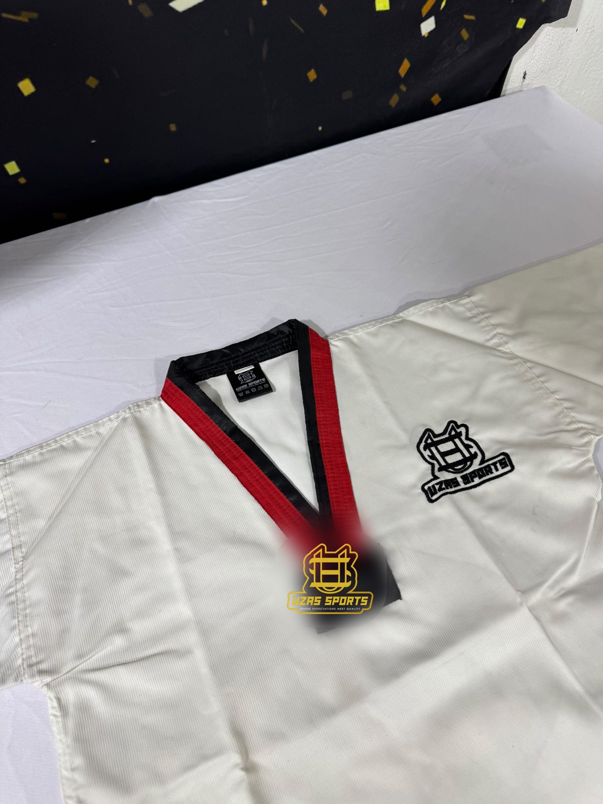 Taekwondo uniform with a red and black V-neck collar and embroidered logo